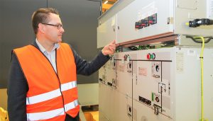 ABB:n Mika Kuusisto esittelee sähkövaraston Suomessa valmistettua ohjaus- ja kommunikaatioyksikköä.