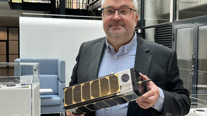 VTT:n johtava tutkija Jussi Säily pitää kädessään W-Cube-nanosatelliitin tarkkaa kopiota. Kuva: VTT.